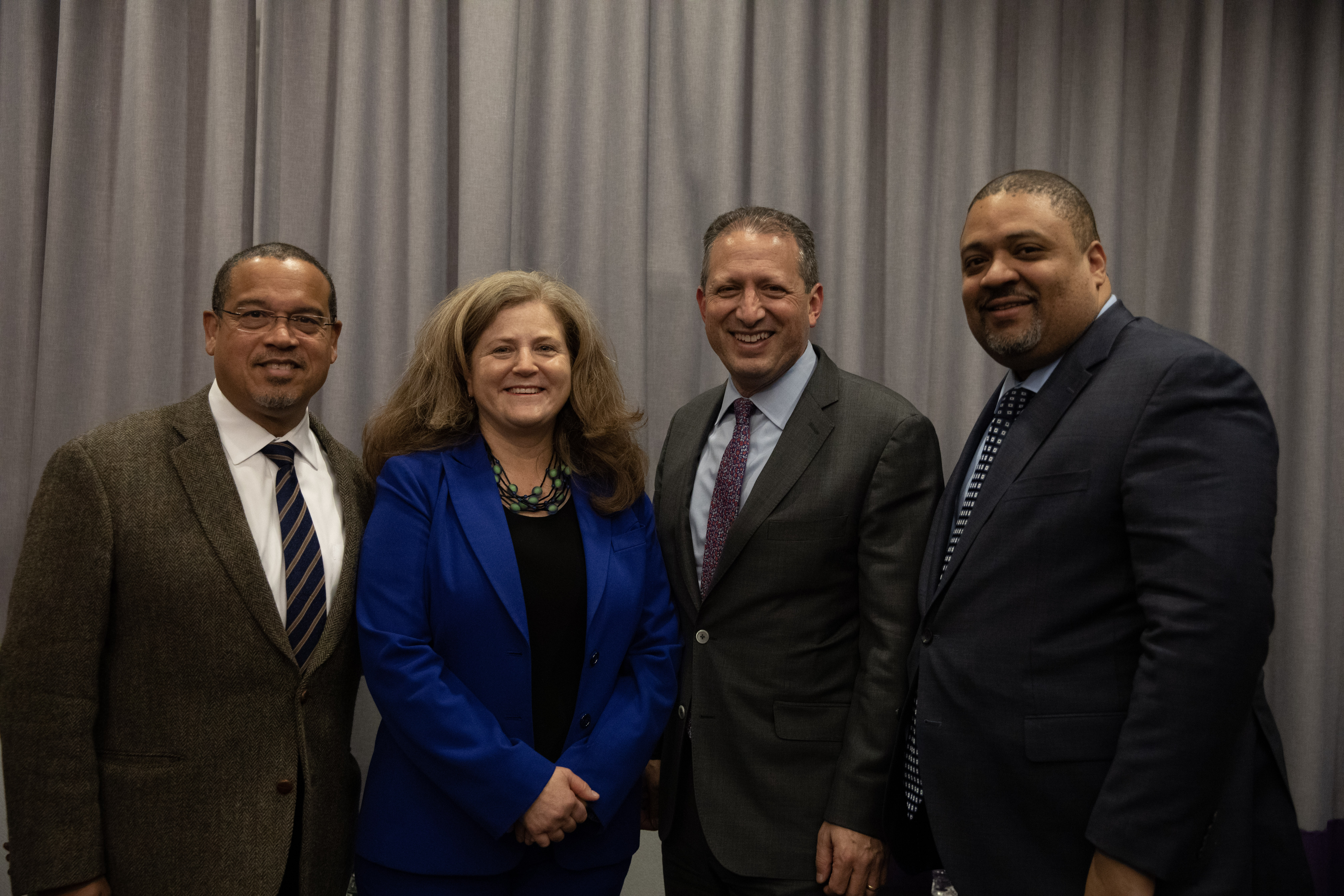 a woman in a blue suit posing with three men in suits