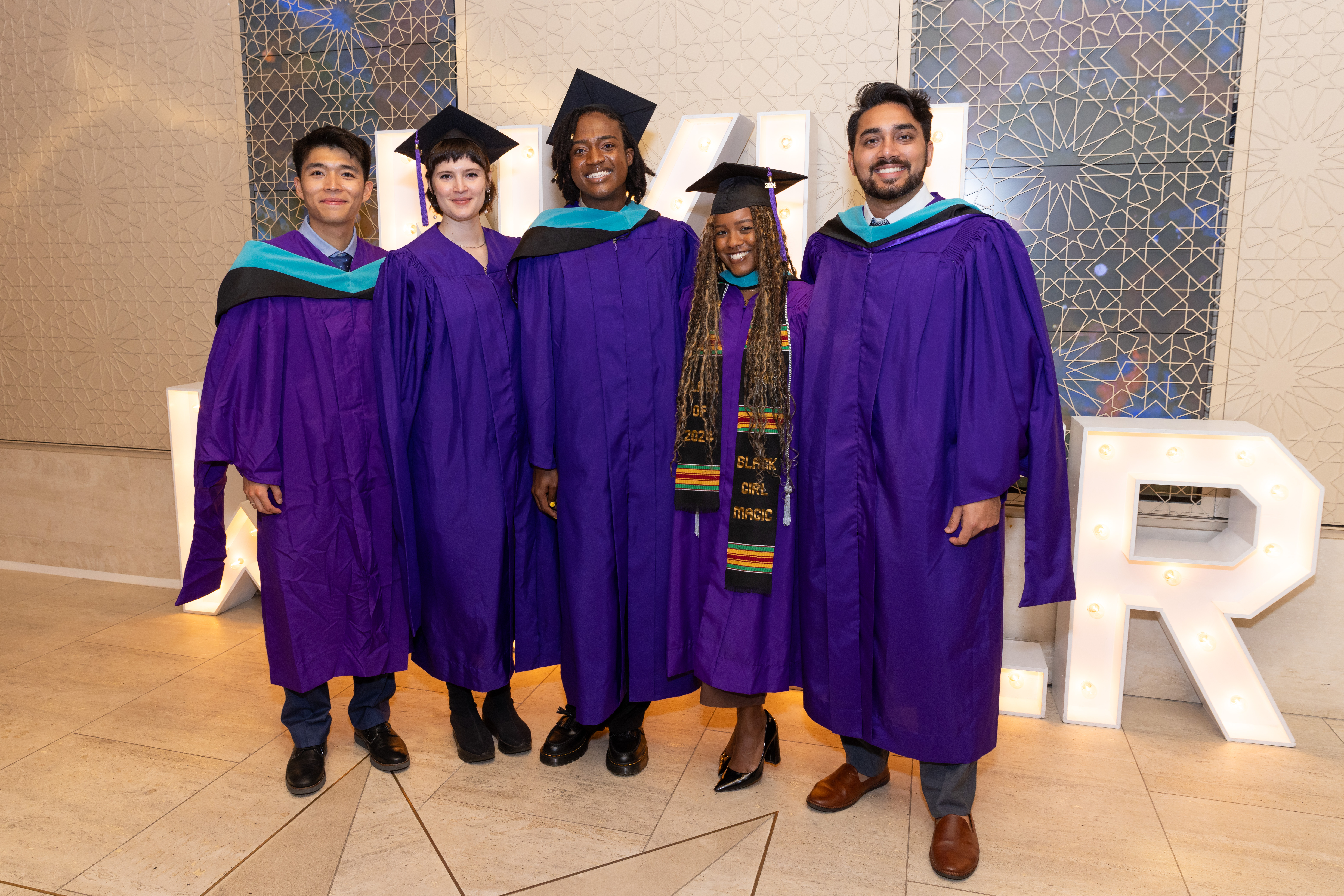 group of students in purple graduation regalia posing for photo