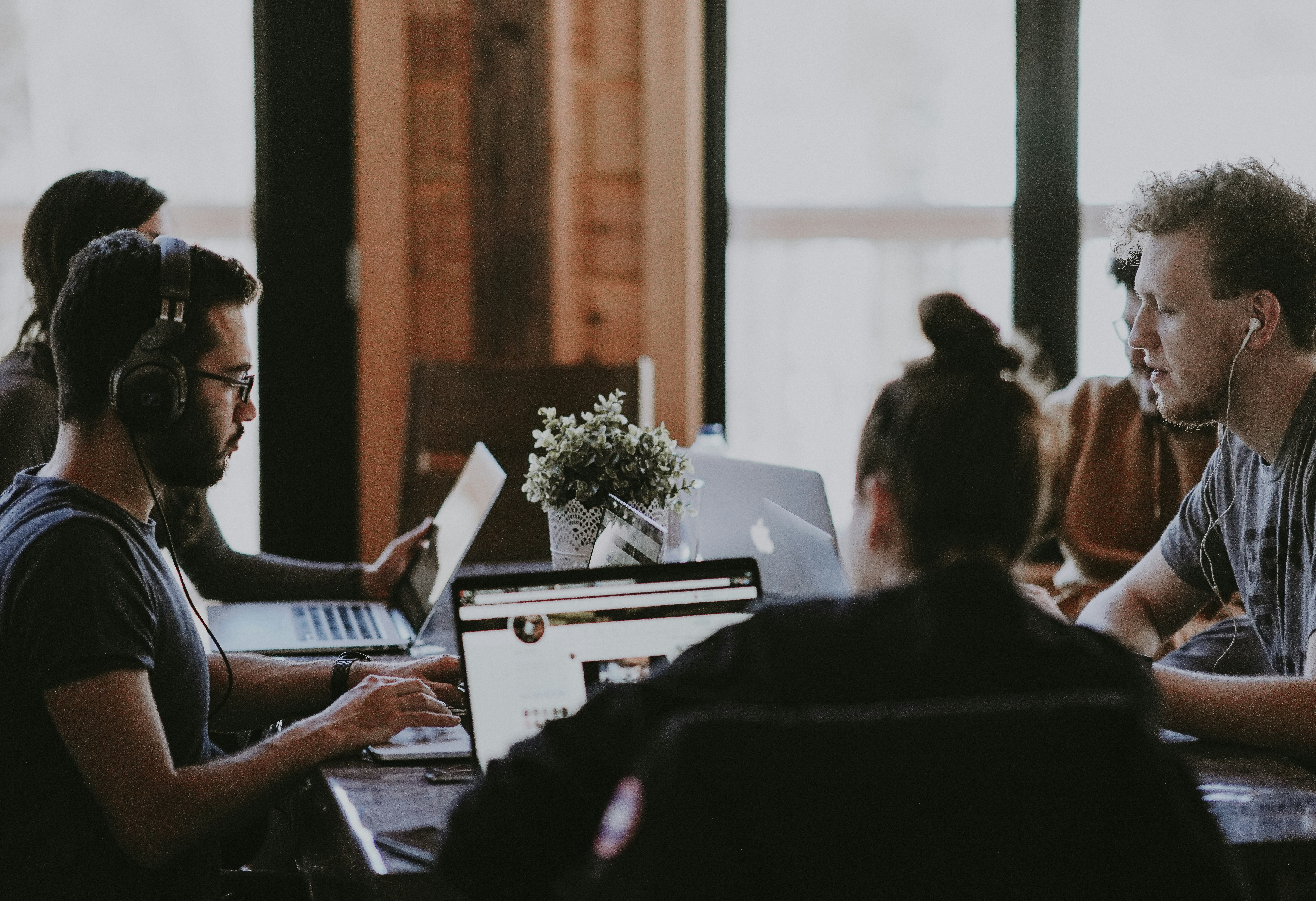 group of people sitting at table with laptops