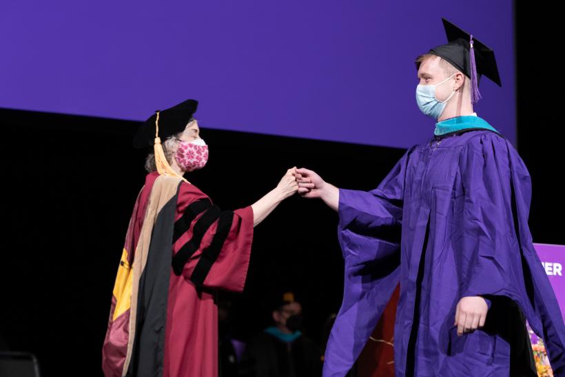 Graduate being greeted by professor Erica Foldy