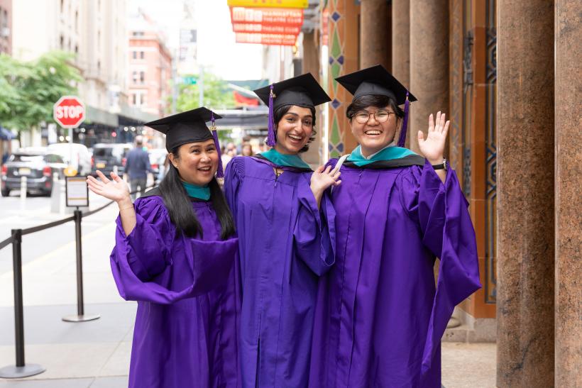 Three graduates outside City Center