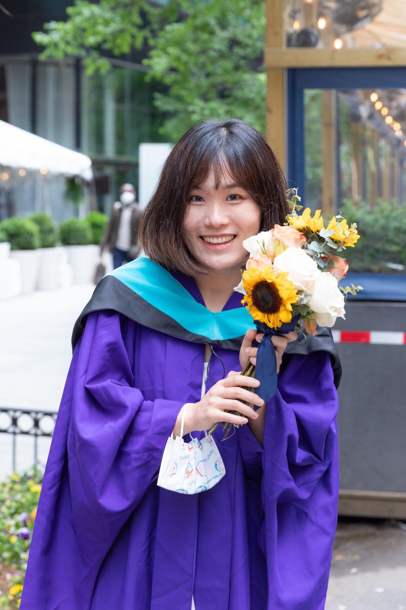 A graduate holding flowers