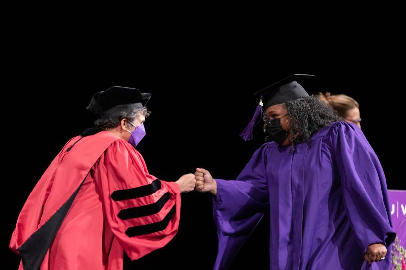 A graduate being greeted as they walk across the stage