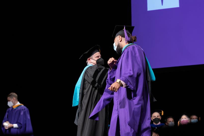 A graduate being greeted as they walk across the stage