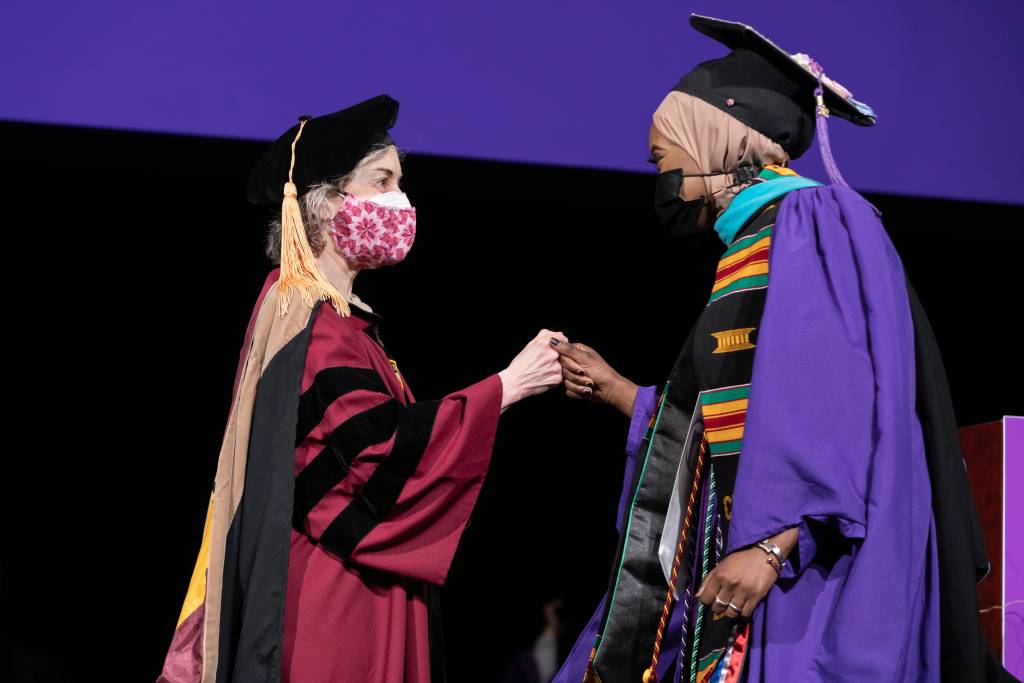 Graduate being greeted by professor Erica Foldy