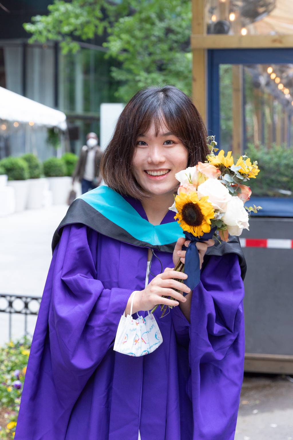 A graduate holding flowers