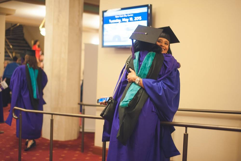 Two people hugging whilst wearing graduation attire
