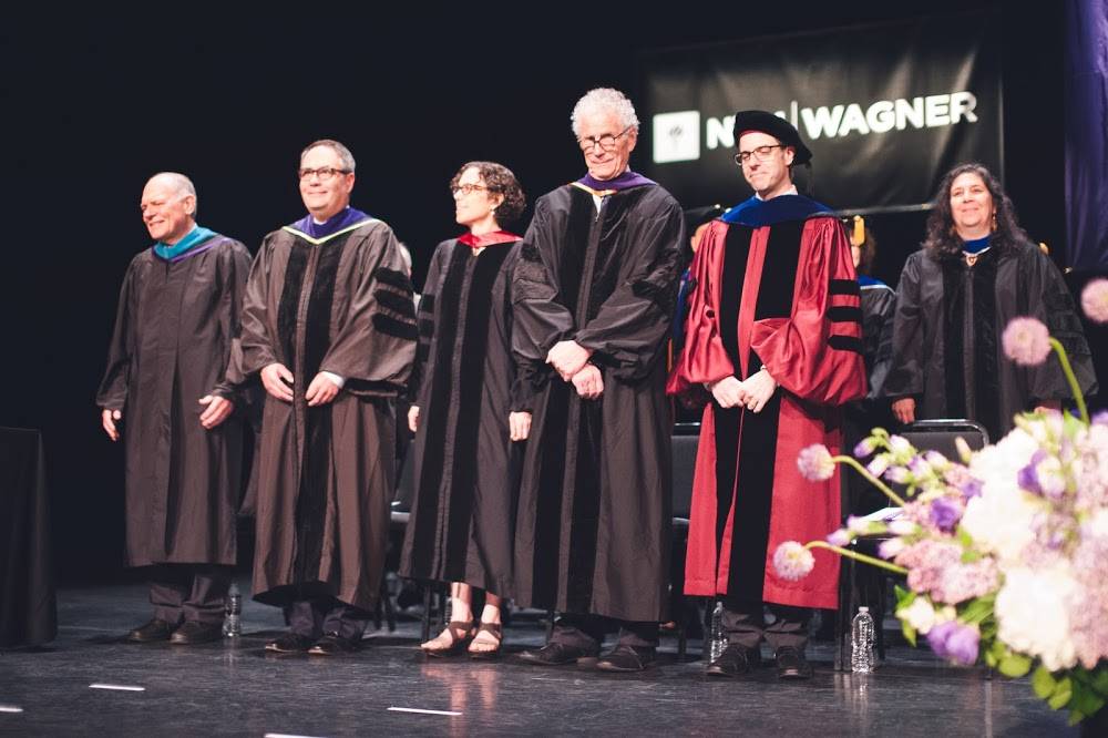 Faculty in academic attire standing on stage