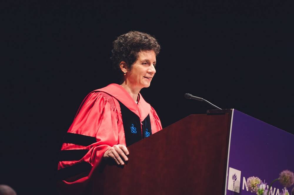 Dean Sherry Glied in academic attired speaking on stage