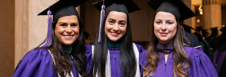 Three women in NYU graduation attire.