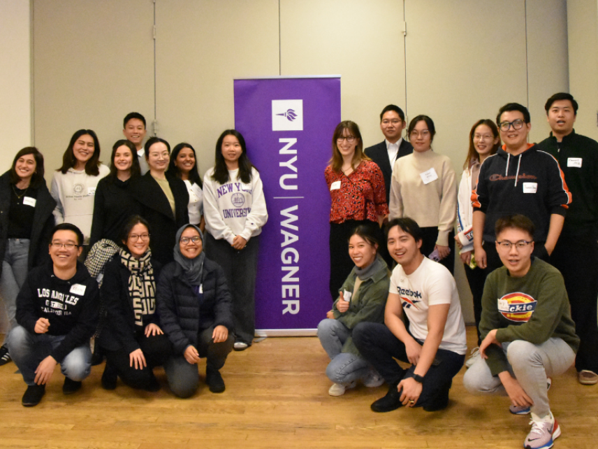 Attendees posing in front of the NYU Wagner banner for a group picture