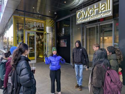 group listening to speaker in front of building 
