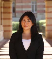 Pictured is a headshot of a young woman with long dark hair in a suit. 