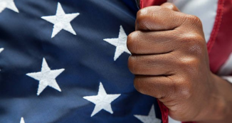 Black person's hand holding the American flag.